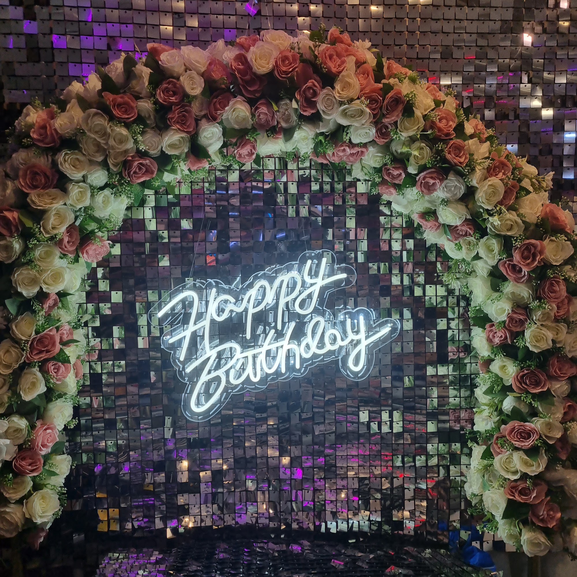 قوس ورد على جدار لامع مع لوحة نيون Happy Birthday